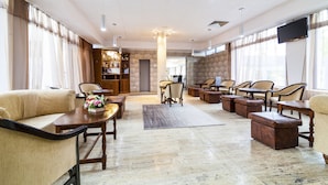 A spacious lobby with a high ceiling, multiple seating areas, and a large screen. - MyContinental Suceava (Suceava)