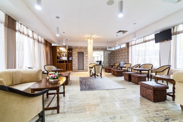 A spacious lobby with a high ceiling, multiple seating areas, and a large screen.