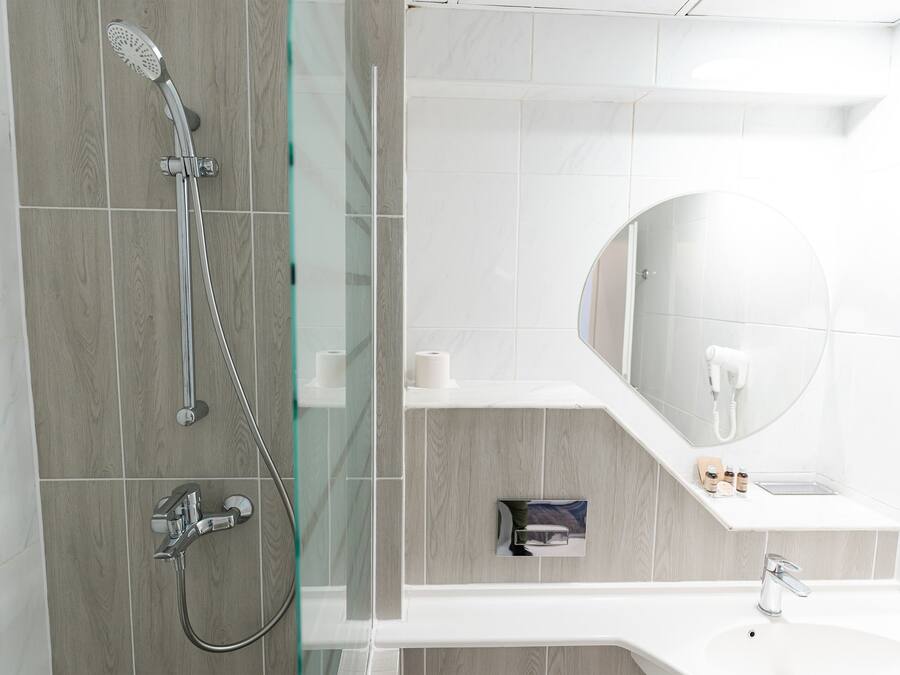 A modern bathroom with a glass-enclosed shower, a vanity with a mirror, and a hairdryer on the wall.