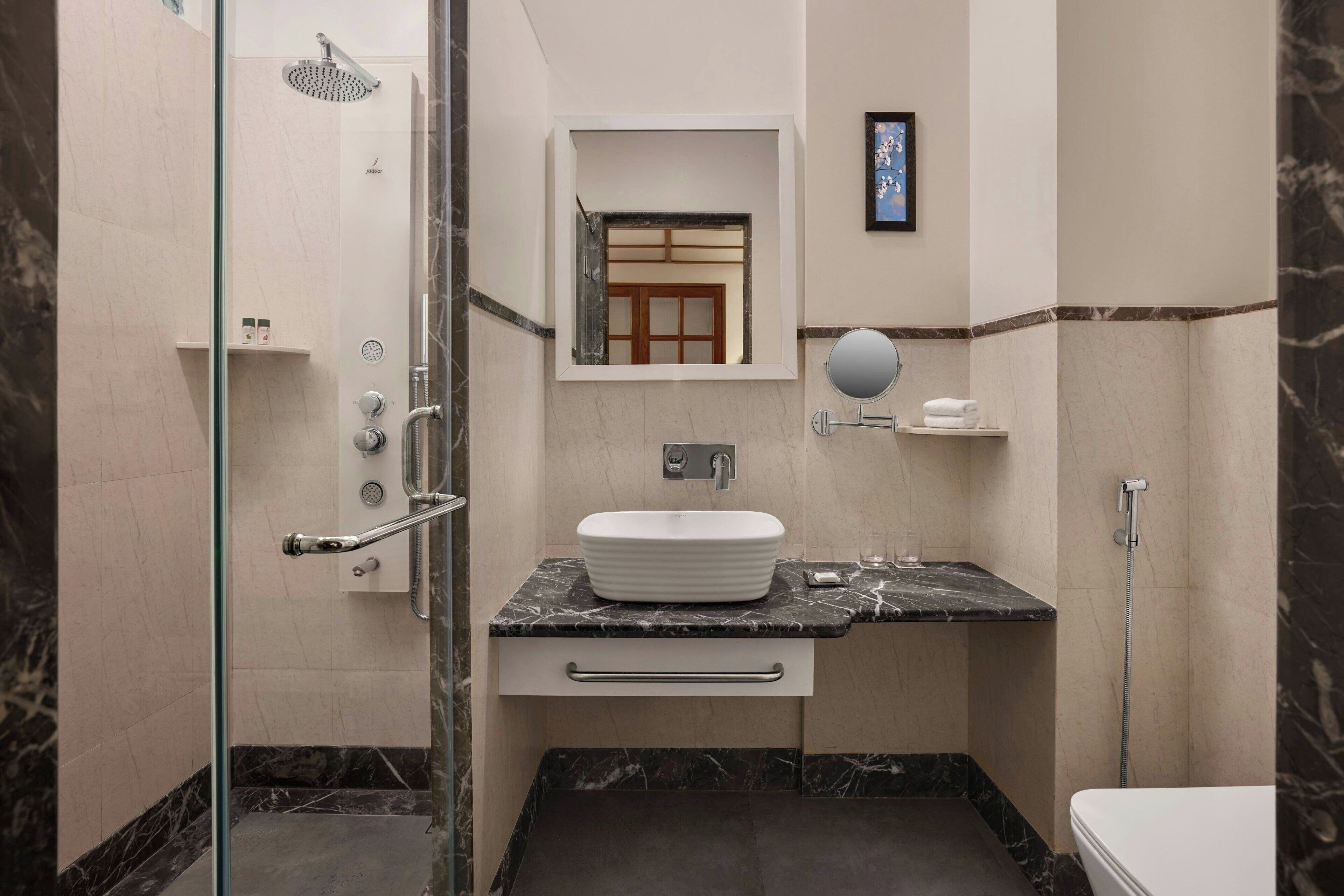 Un baño moderno con ducha de vidrio, lavamanos de mármol y un inodoro.
