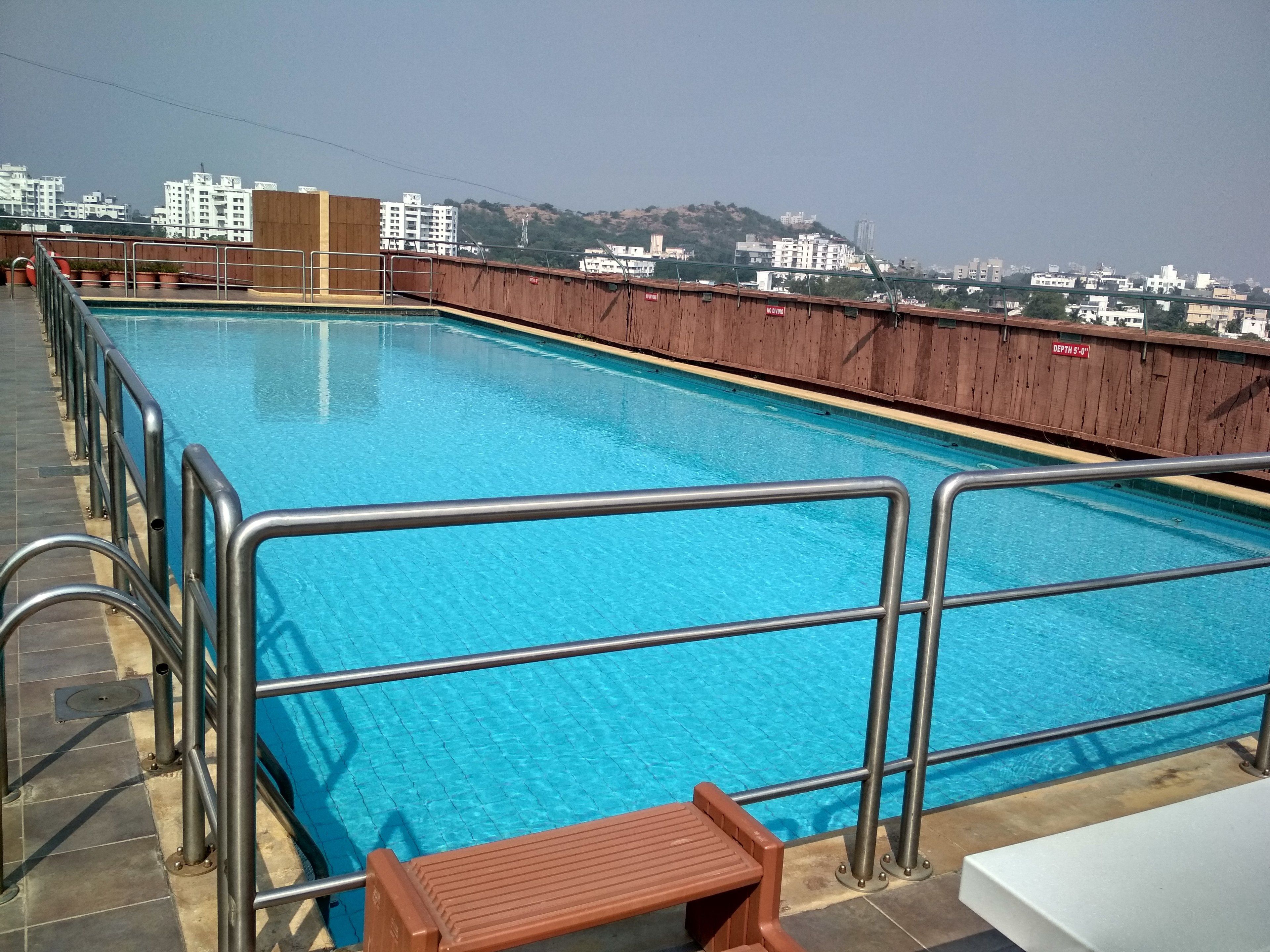 Una piscina rectangular con barandillas de metal y una terraza de madera.
