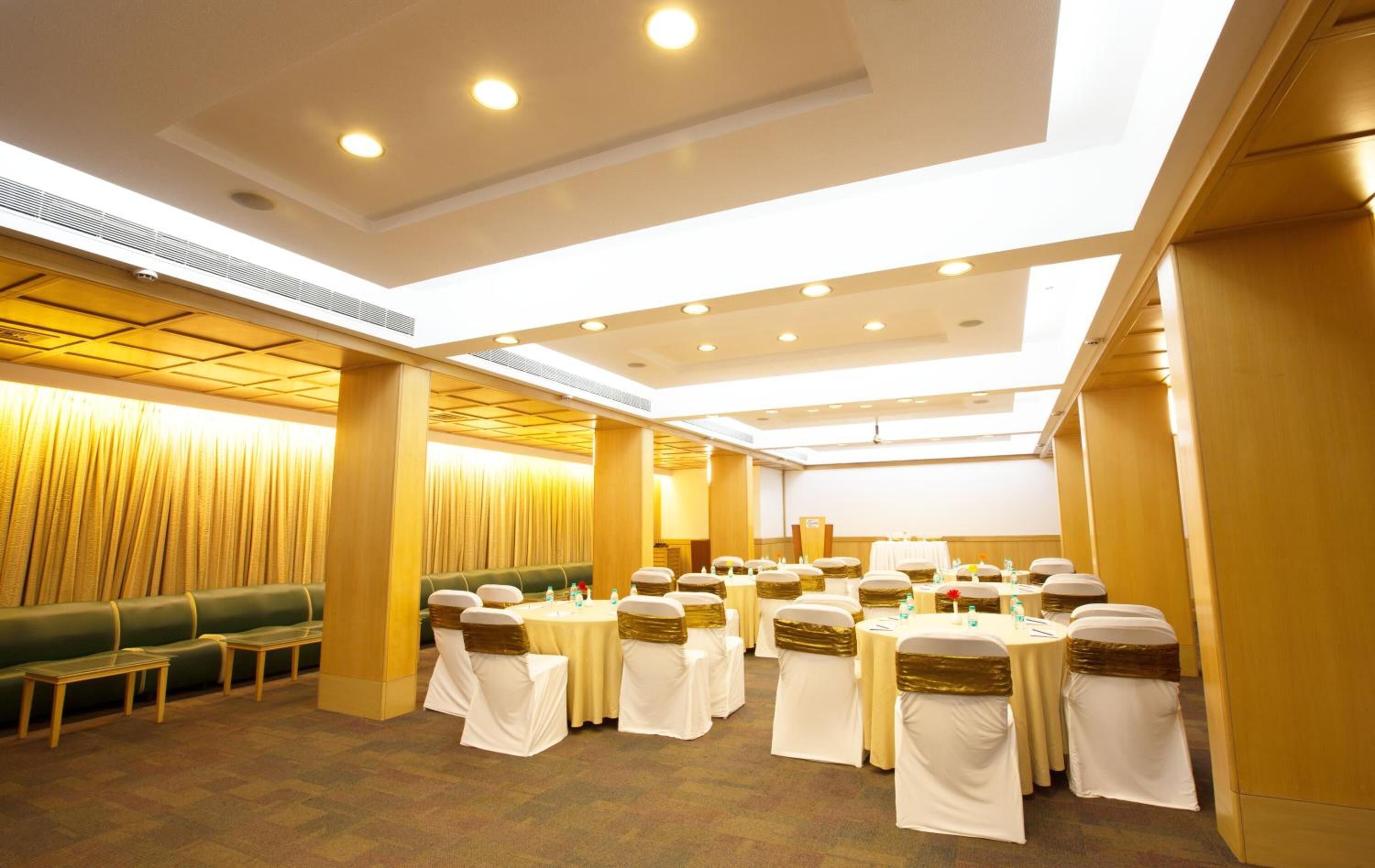 A conference room with round tables, white tablecloths, and gold sashes.