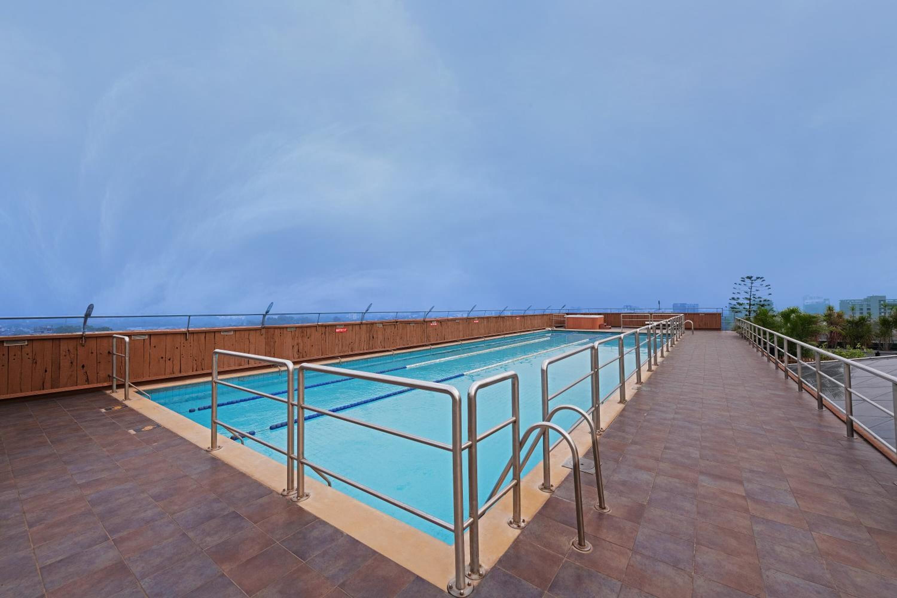 A rooftop pool with a wooden deck and metal railings.