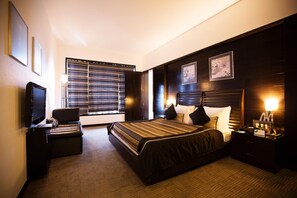A hotel room with a large bed, a TV, a desk, and a window with blinds. - E-Square The Fern Pune, Series by Marriott (Pune)