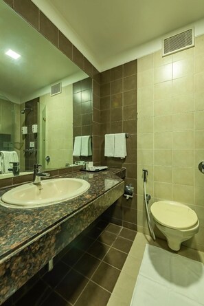 A bathroom with two sinks, a toilet, a mirror, and a shower area.