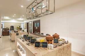 A buffet area with various food stations labeled with names like "VADA," "IDLI," and "SAMBAR."