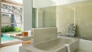 A modern bathroom with a large bathtub, a glass shower enclosure, and a view of a swimming pool. - Uma Sapna Seminyak (Seminyak)