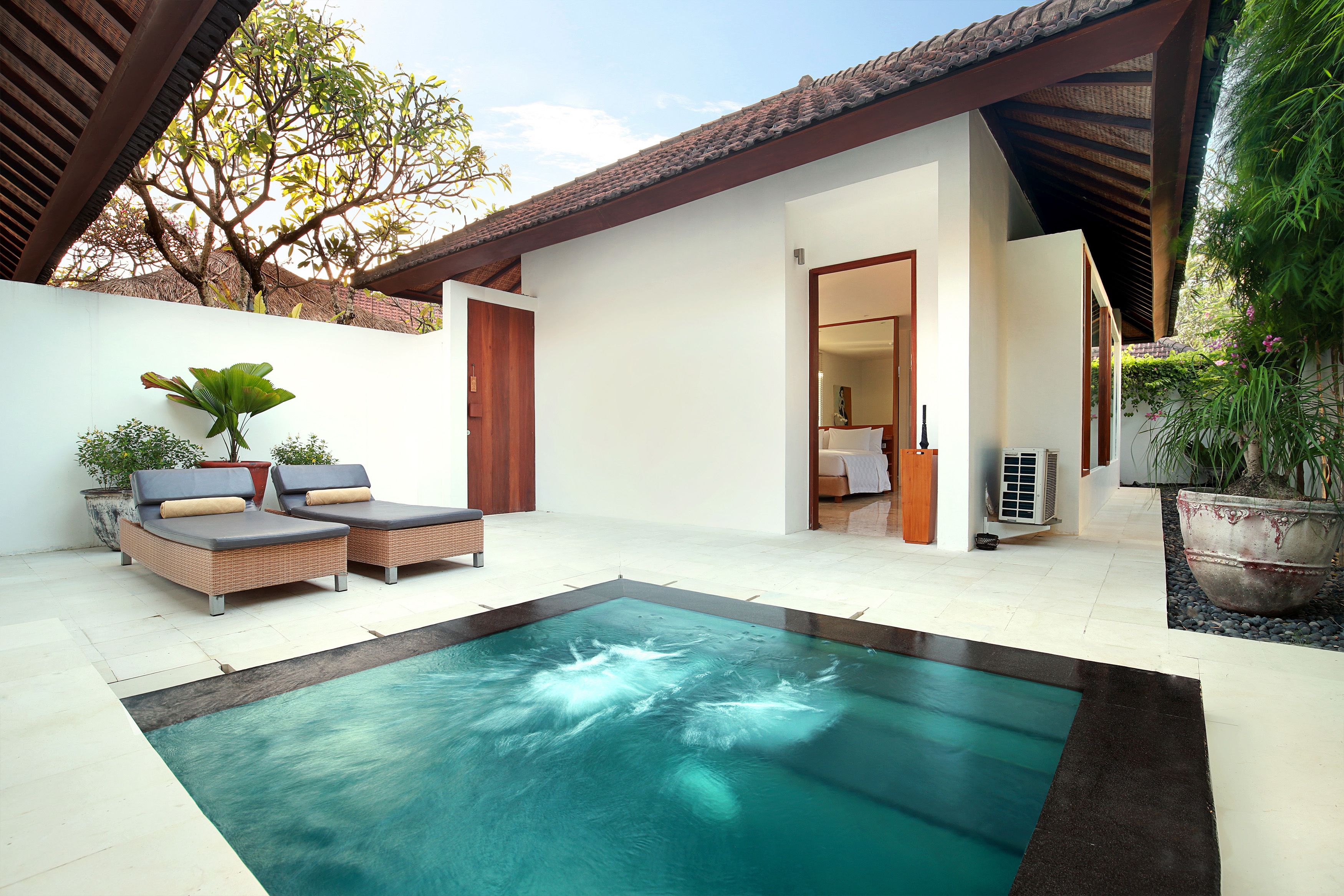 A swimming pool with lounge chairs, a covered patio, and a view of the surrounding area.