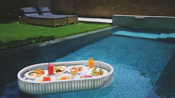 A poolside area with a floating dining table.