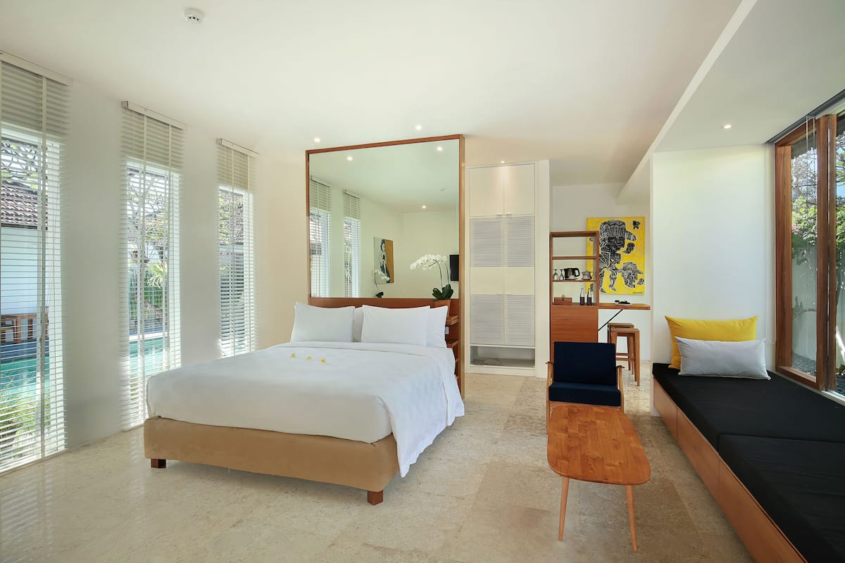 Een moderne hotelkamer met een groot bed, een bureau, een bank en een grote spiegel.