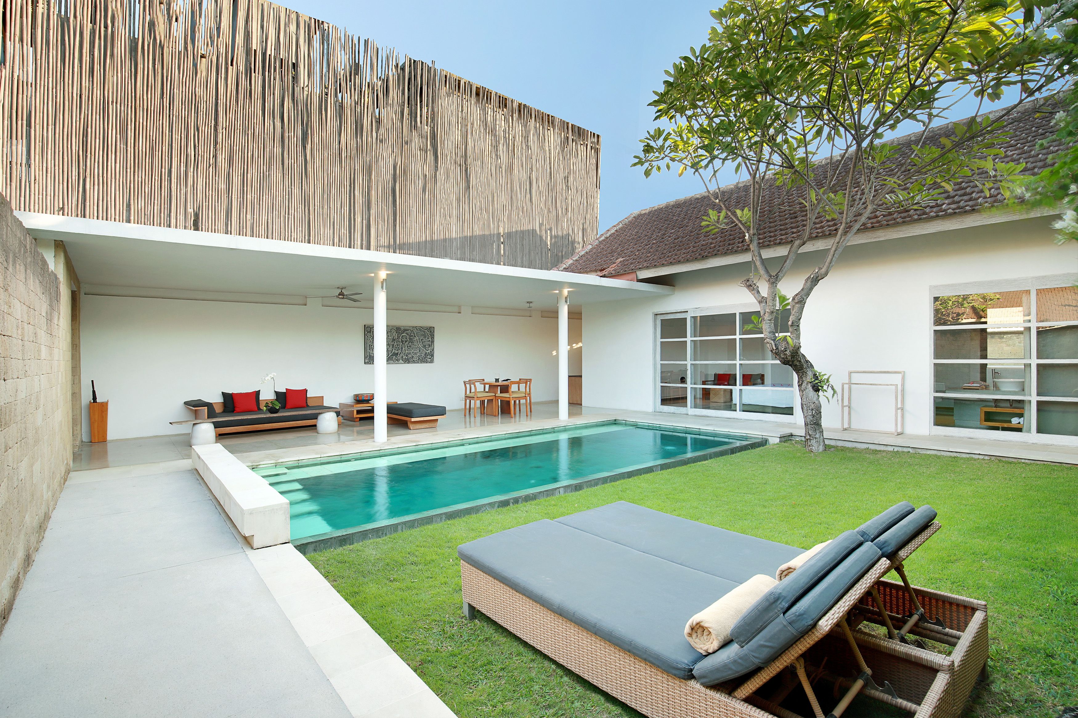 A modern house with a swimming pool, a covered patio, and a well-maintained lawn.
