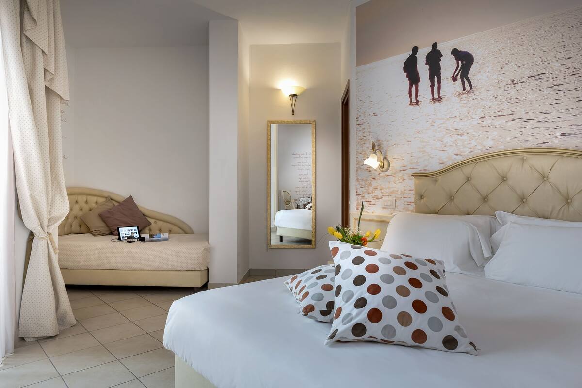 Una habitación de hotel con una cama, un sofá, un espejo y una pared decorada.