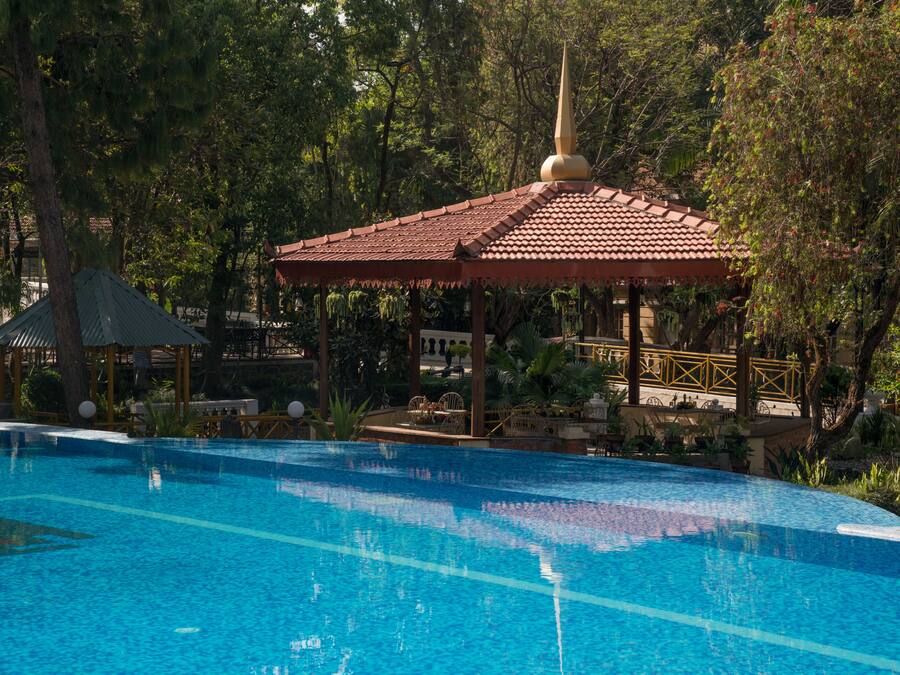 Una piscina con un gazebo e vegetazione circostante.