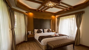 Un dormitorio espacioso con una cama grande, piso de madera y un banco.