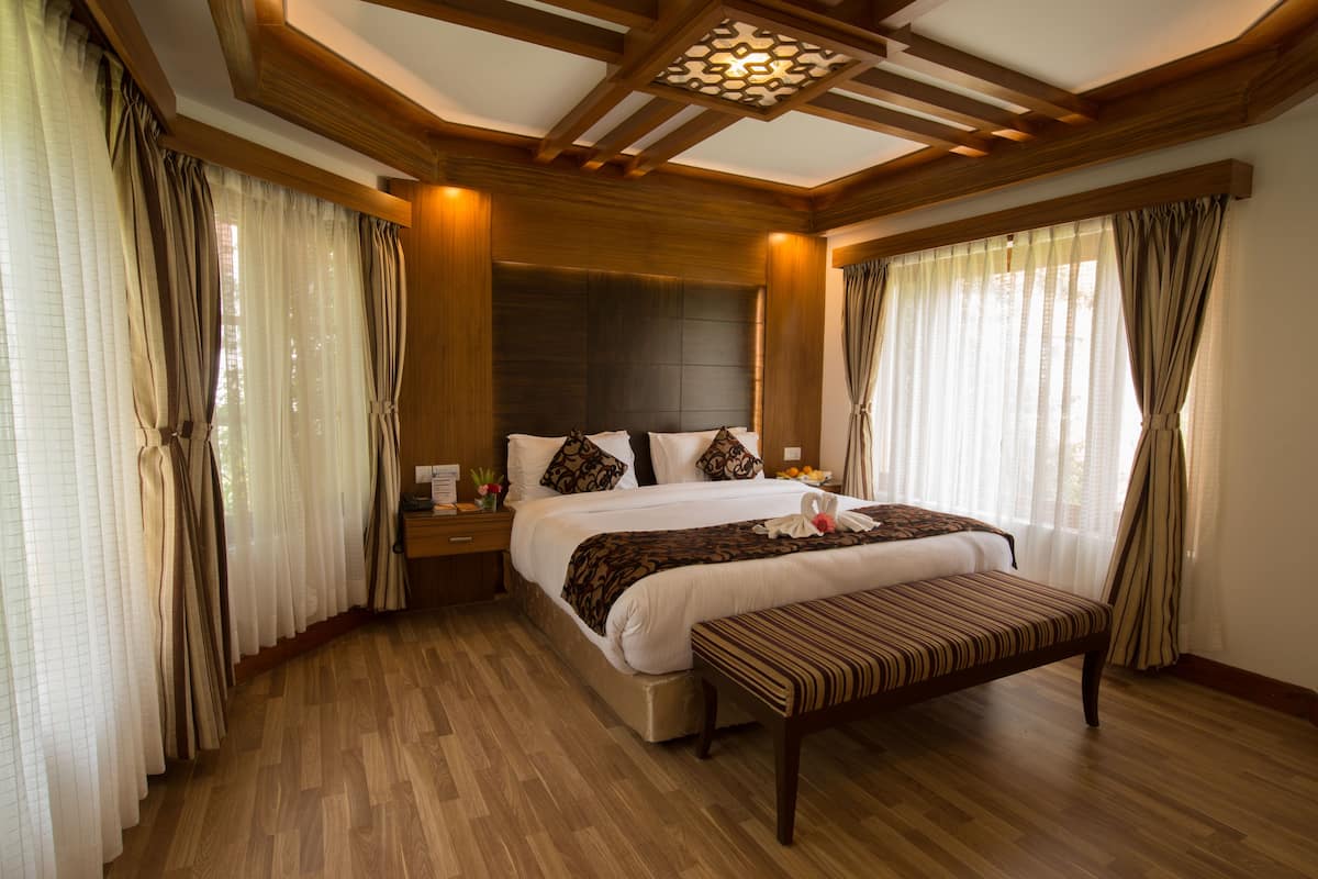 Quarto espaçoso com cama grande, piso de madeira e um banco.