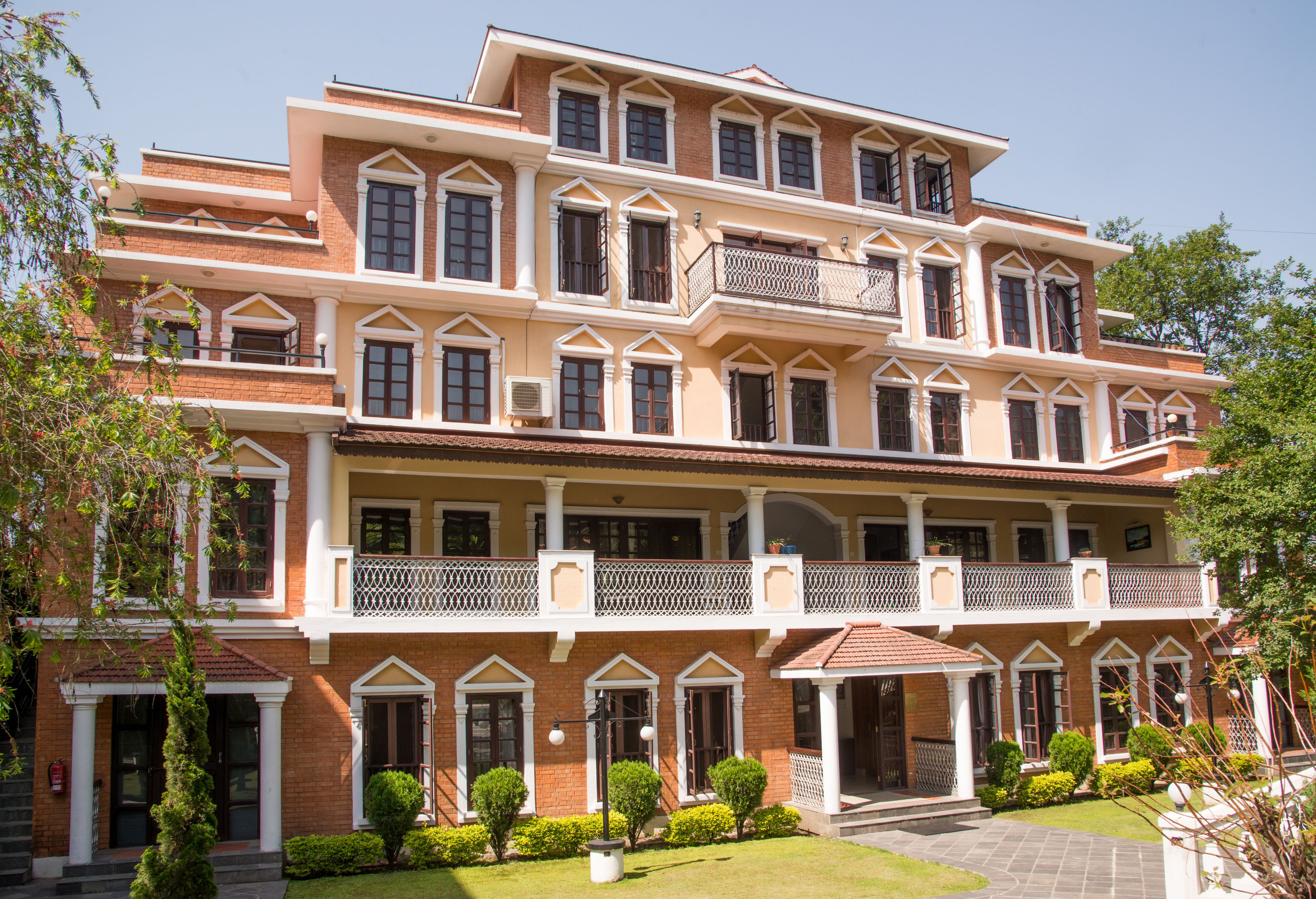 A multi-story building with a symmetrical facade, multiple balconies, and a central entrance with steps leading up to it.