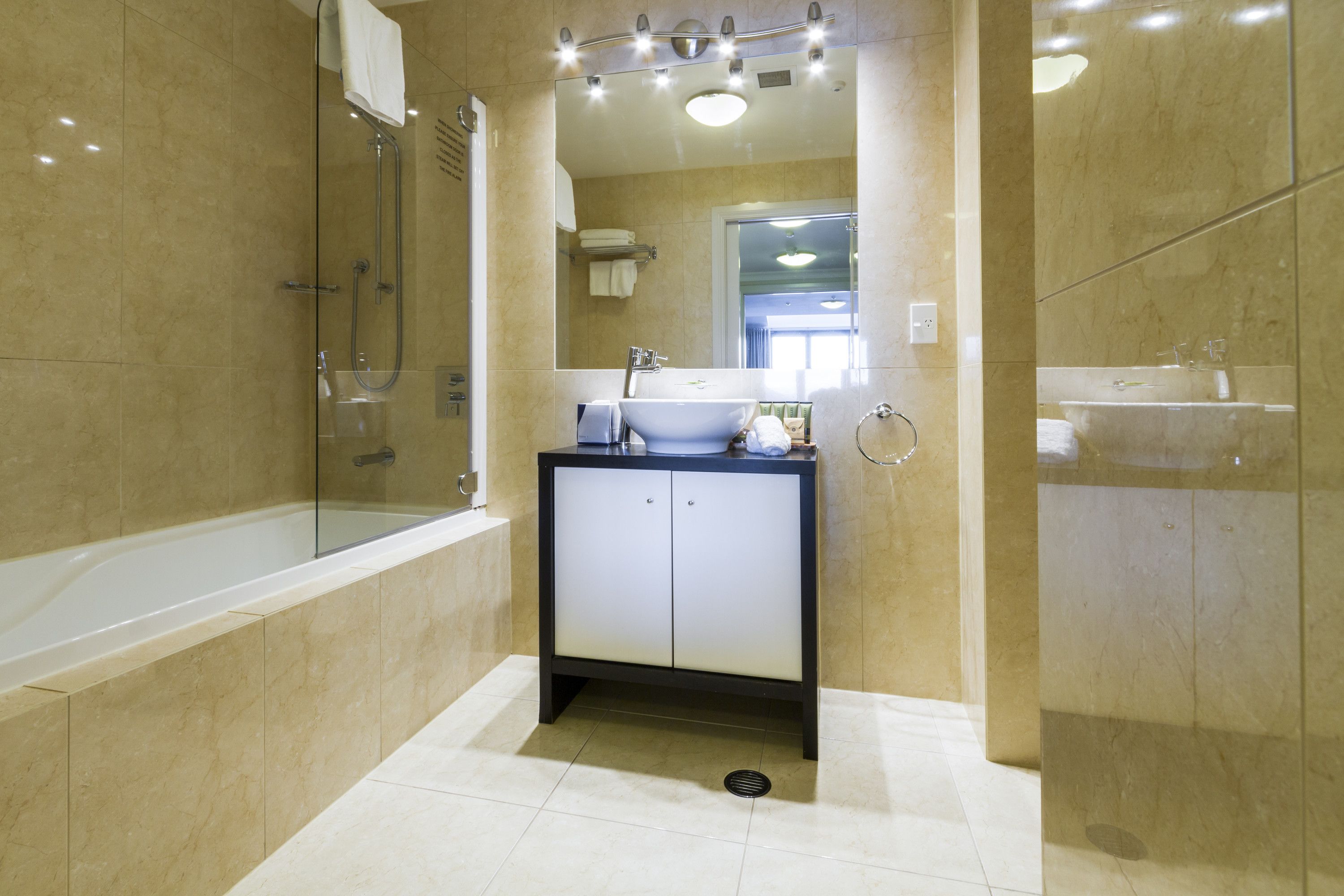 A modern bathroom with a glass-enclosed shower, a sink with a mirror above, and a vanity with cabinets.