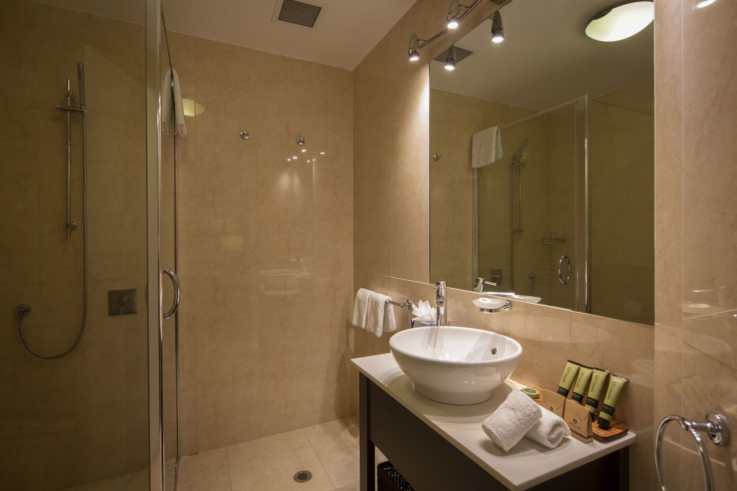 A modern bathroom with a glass-enclosed shower, a white sink, and a large mirror.