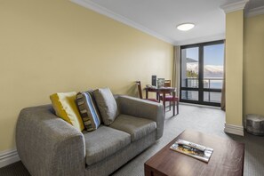 A living room with a sofa, a coffee table, and a view of mountains through a large window.