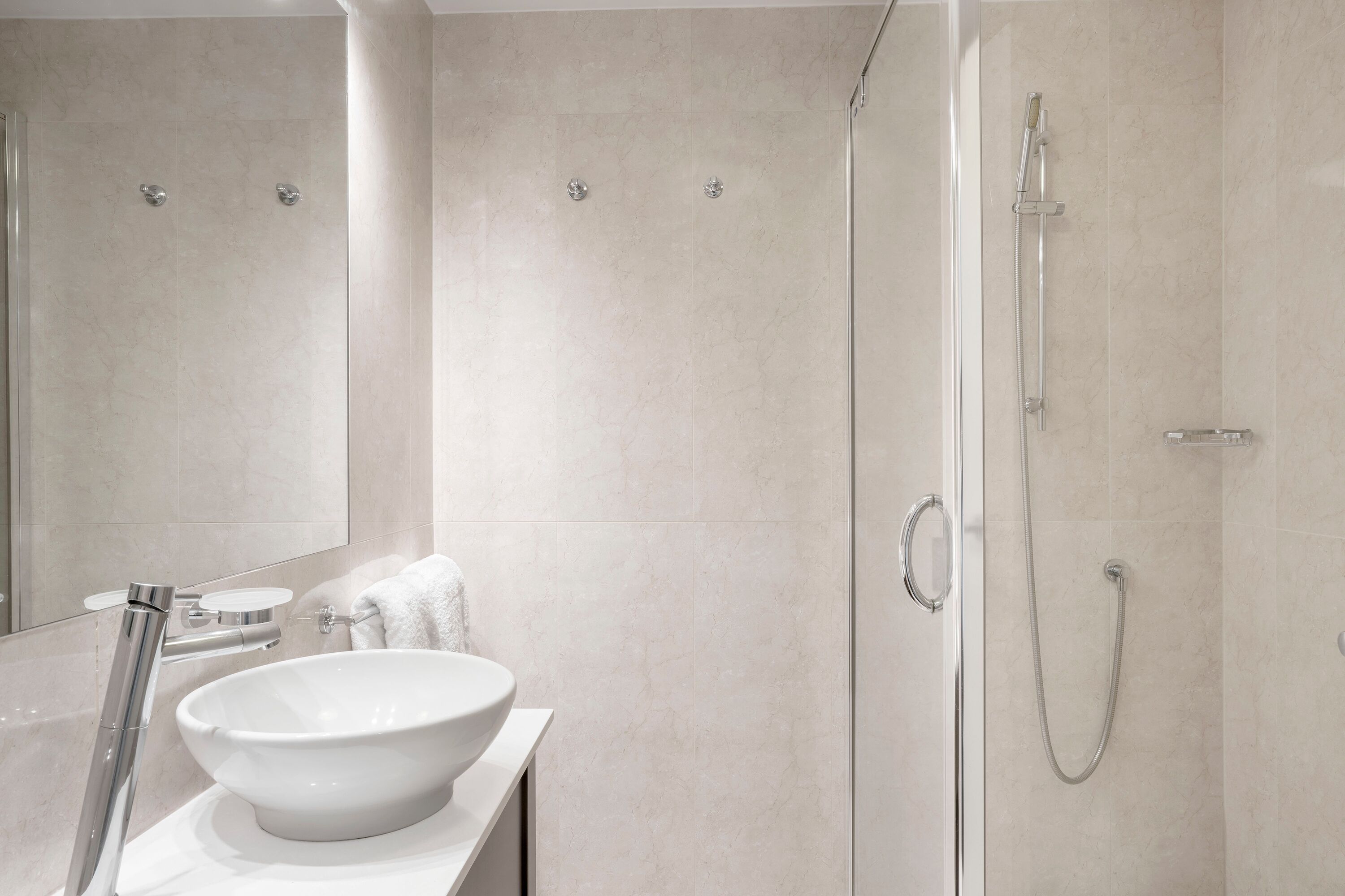 A modern bathroom with a large white sink, a glass shower enclosure, and a mirror.