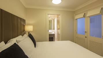 Hotelkamer met een groot bed, een bedlampje, een garderobe met spiegel en een zichtbare badkamer door een open deur.