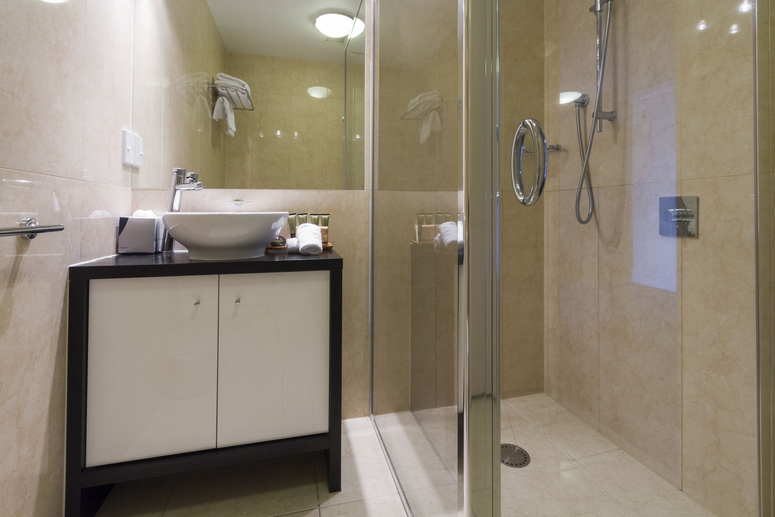 A modern bathroom with a glass-enclosed shower, a white sink, and a black-framed cabinet.