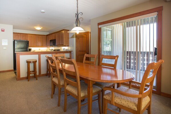 A kitchen with wooden cabinets, a refrigerator, and a dining area with a wooden table and chairs.