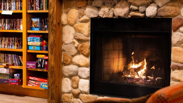 A cozy living room with a stone fireplace, a bookshelf filled with books, and a comfortable seating area.