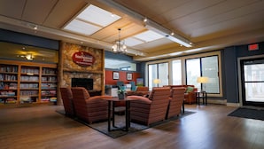 A cozy lounge area with a stone fireplace, comfortable seating, and a bookshelf filled with books.