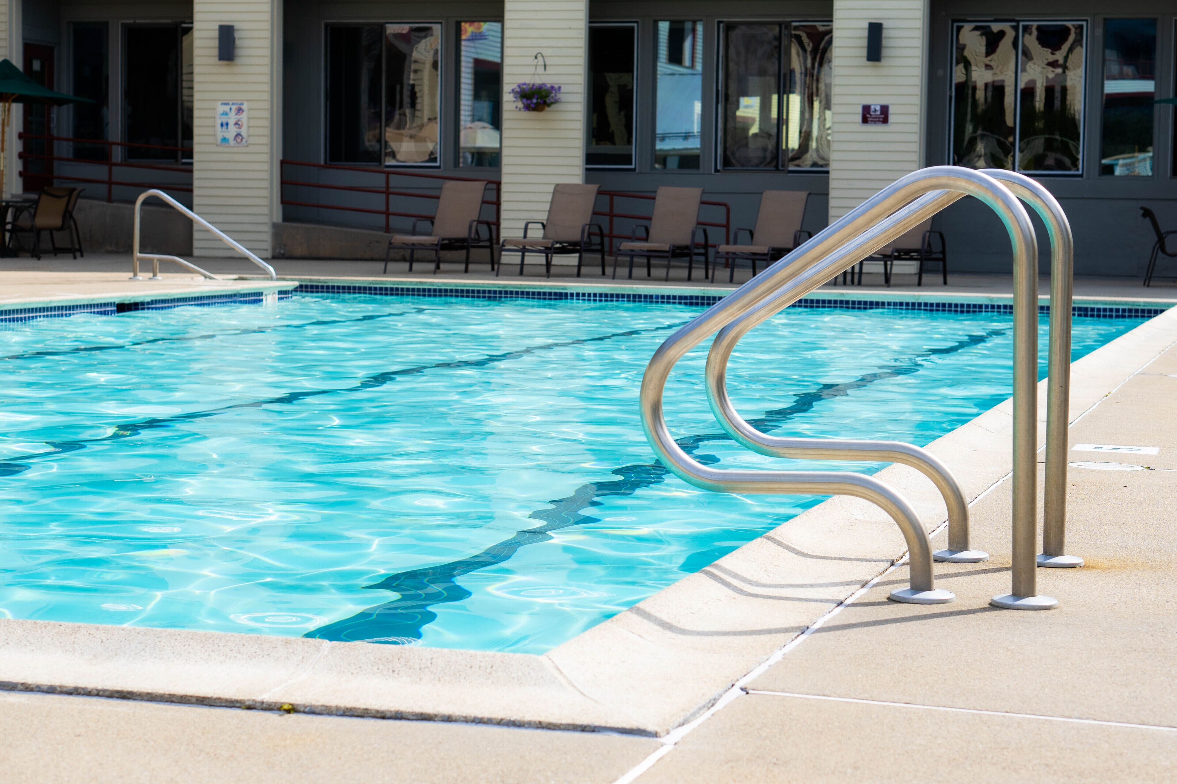 Una piscina con barandillas metálicas y sillas de descanso.