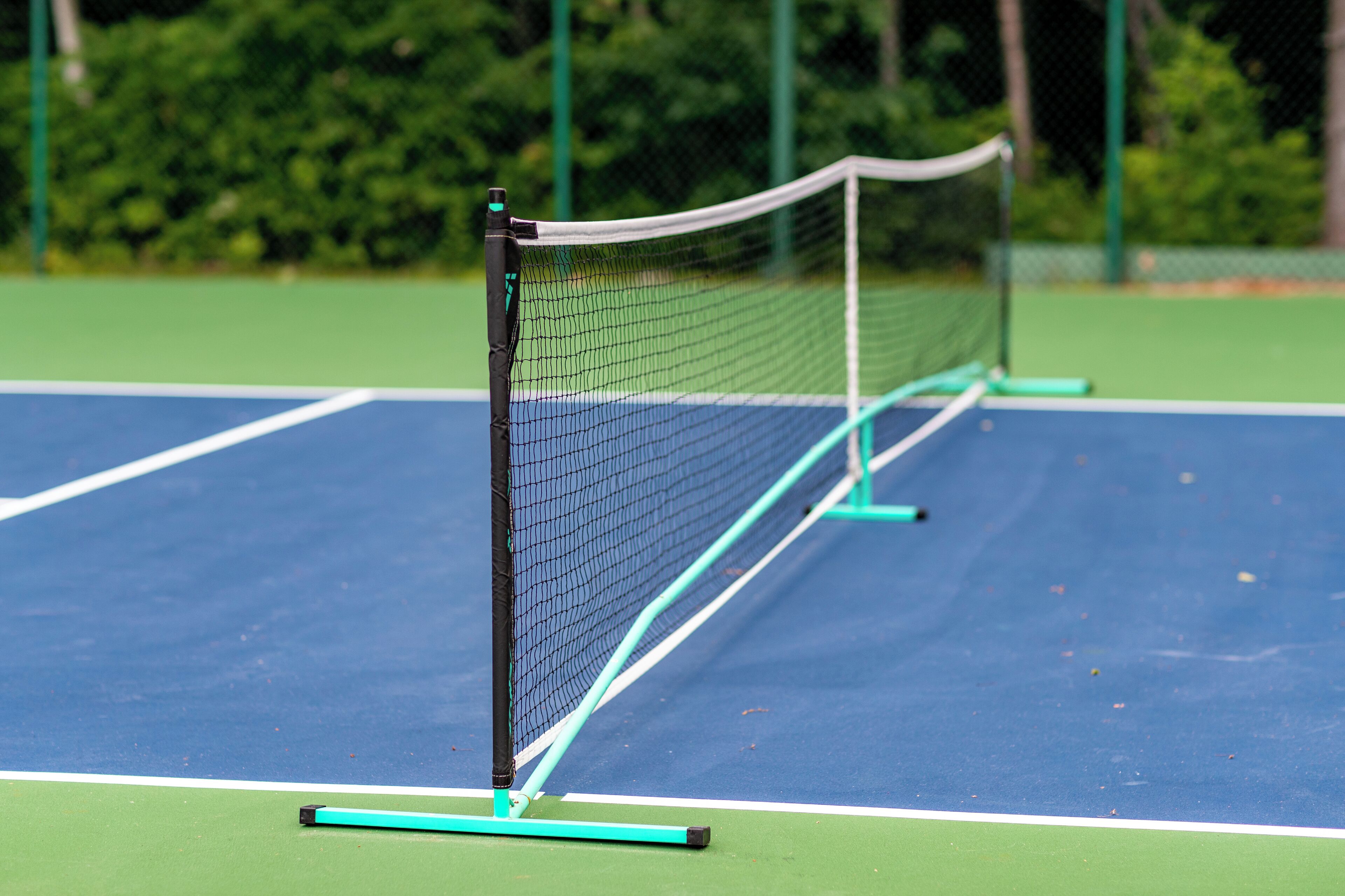 Una pista de tennis amb xarxa i línies delimitadores verdes.