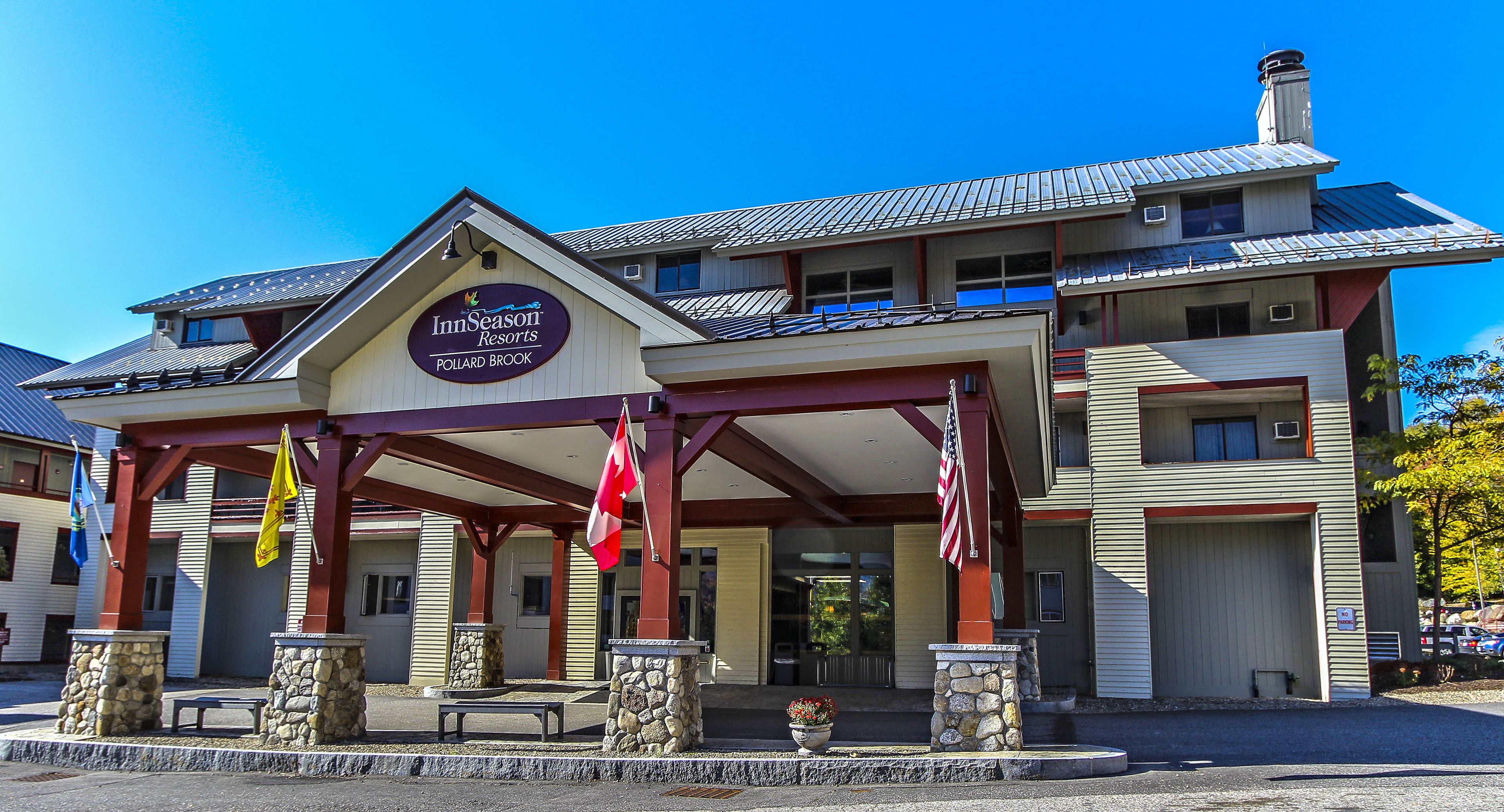 A hotel with a covered entrance, stone pillars, and flags.