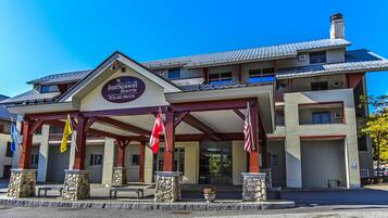 A hotel with a covered entrance, stone pillars, and flags.