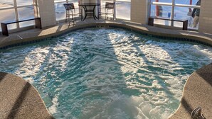 A hot tub with a no diving sign, surrounded by windows and a view of a fenced area.