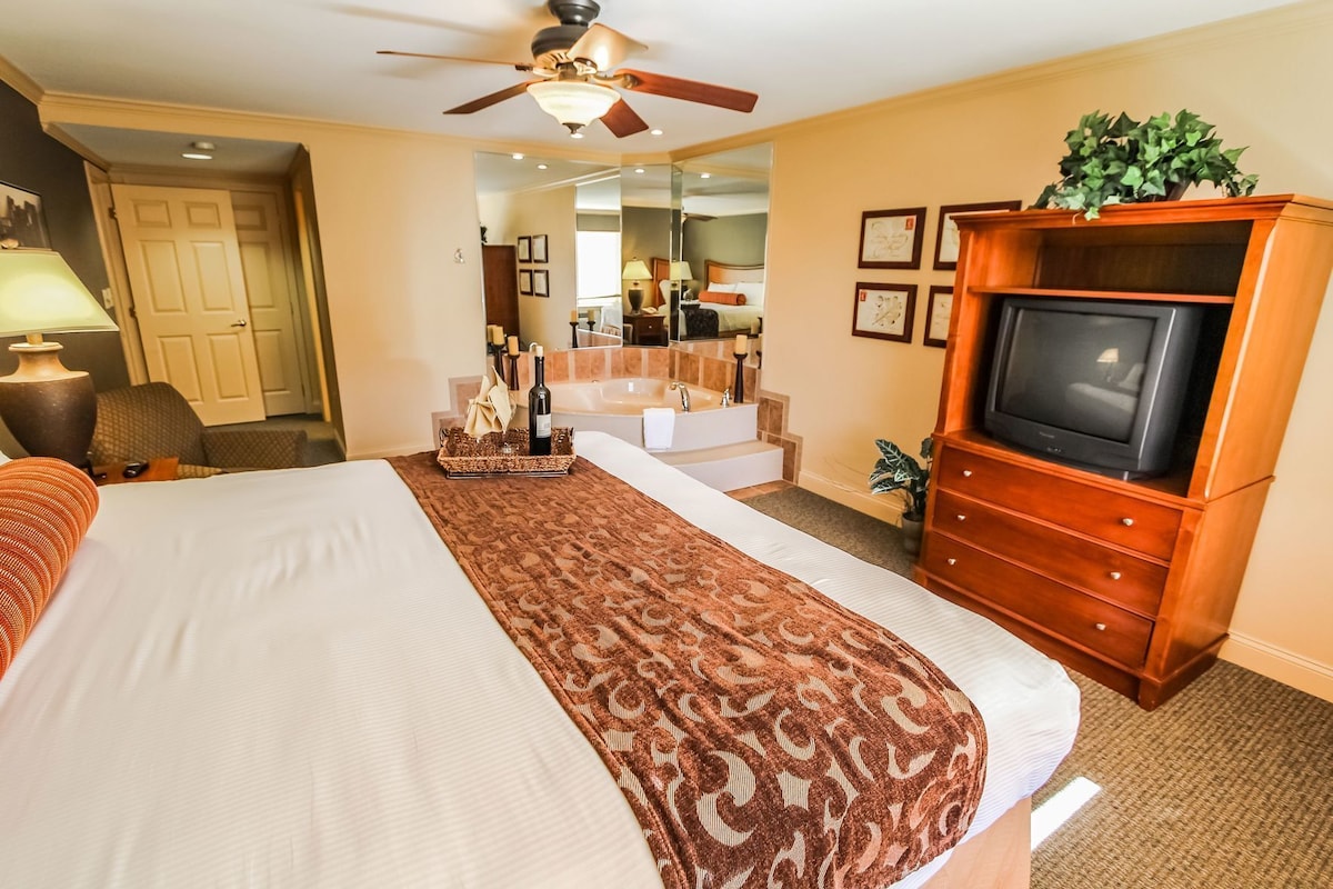 Habitación de hotel con cama, televisión, baño y una escalera que conduce a otra habitación.