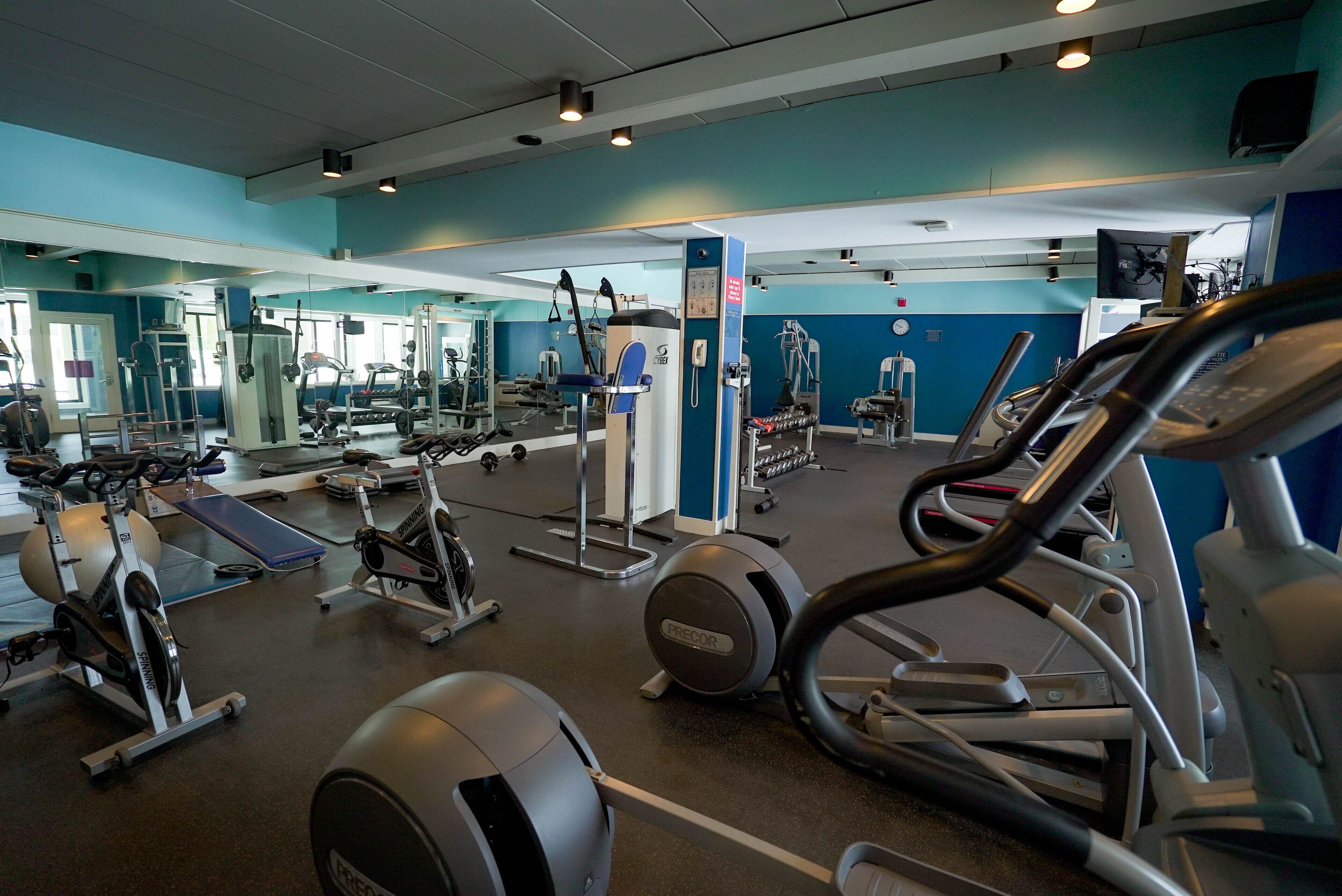 A gym with various exercise equipment including treadmills, elliptical machines, and weight machines.