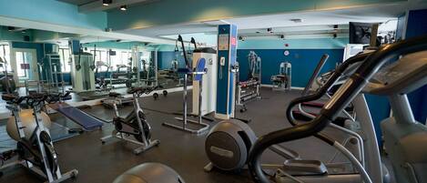 A gym with various exercise equipment including treadmills, elliptical machines, and weight machines.