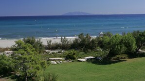 A beach with clear blue water, a distant mountain, and green vegetation. - Résidence Cala Bianca (Borgo)