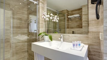 Un baño moderno con un espejo grande, un lavabo blanco y una planta en maceta.