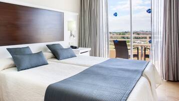 Ein Hotelzimmer mit zwei Betten, einem großen Fenster und Blick auf die Stadt.