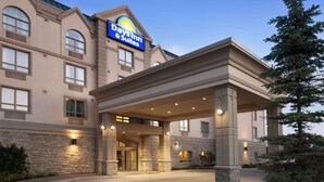 A Days Inn & Suites building with a stone facade, large windows, and a prominent sign. - Days Inn & Suites by Wyndham Collingwood (Collingwood)