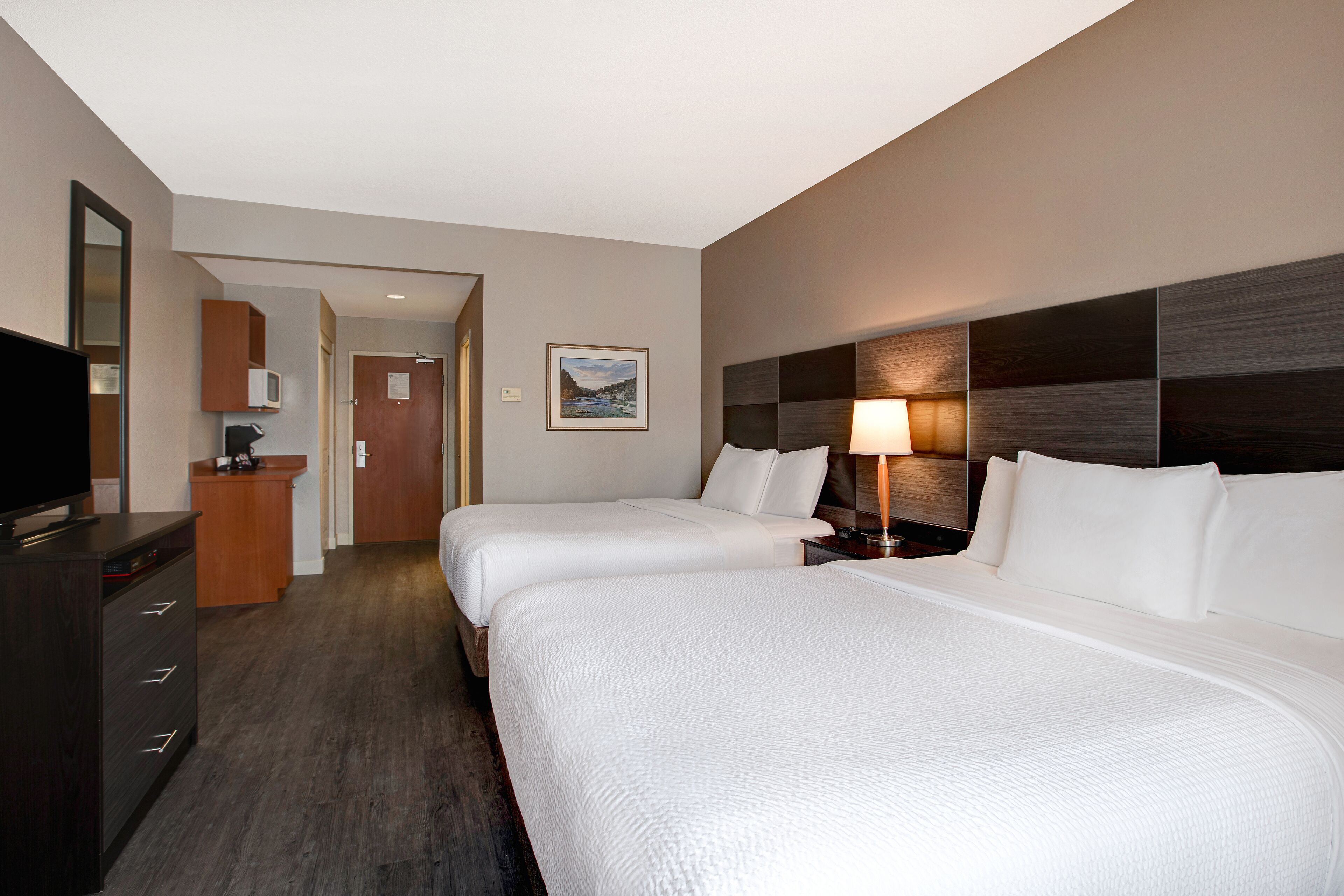 Una habitación de hotel con dos camas, televisión, escritorio y baño.