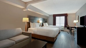A hotel room with a large bed, a sofa, a desk, and a TV. - Days Inn & Suites by Wyndham Collingwood (Collingwood)