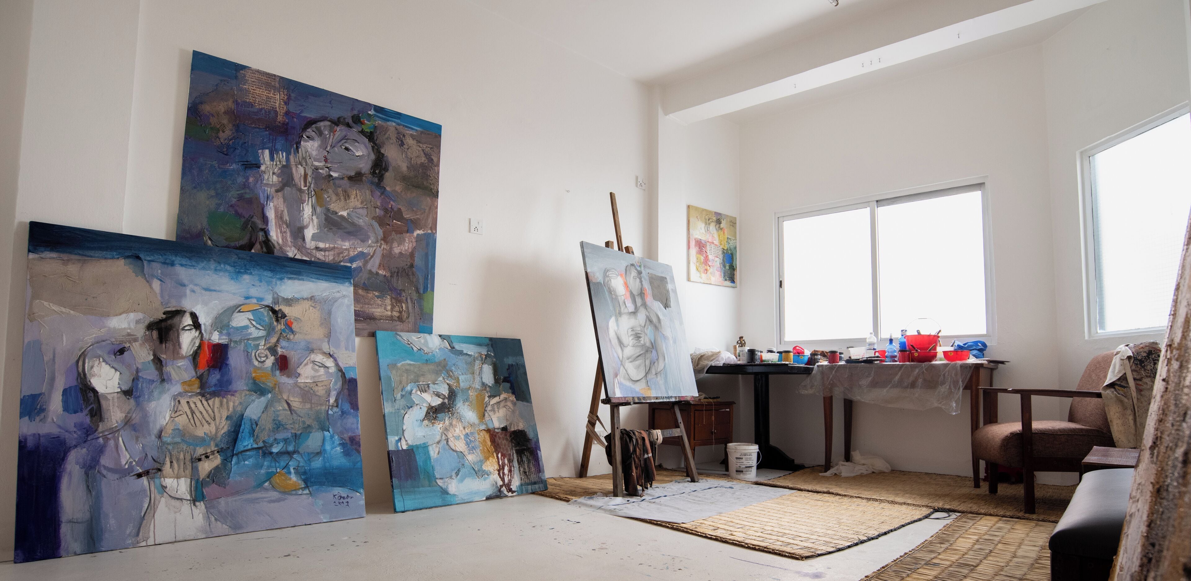 An artist's studio with large canvases, an easel, and art supplies.