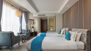 A modern hotel room with a large bed, two armchairs, a desk, and a large window with curtains. - Kathmandu Guest House by KGH Group (Kathmandu)