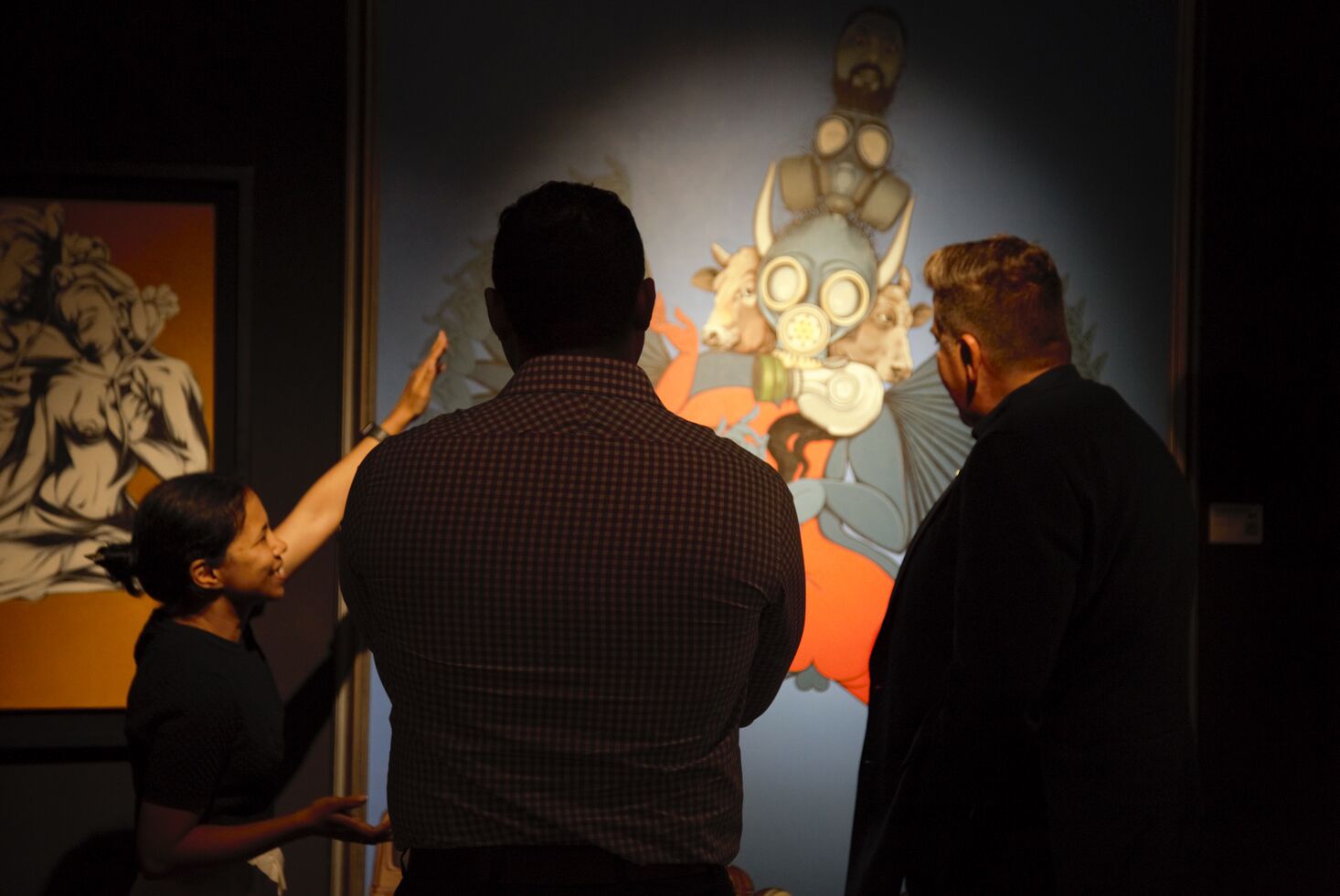 A group of people observing a large, colorful artwork.
