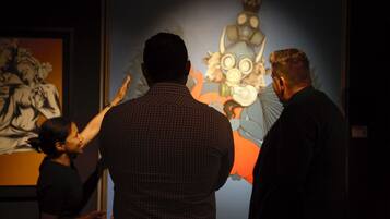 A group of people observing a large, colorful artwork.
