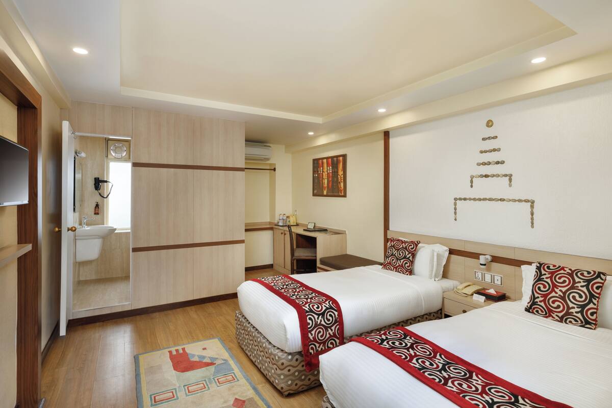 Une chambre d’hôtel avec deux lits, un bureau, une salle de bain et une télévision.