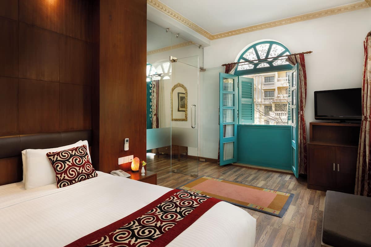Une chambre d’hôtel avec un grand lit, une télévision, une armoire et une salle de bain visible à travers une porte ouverte.