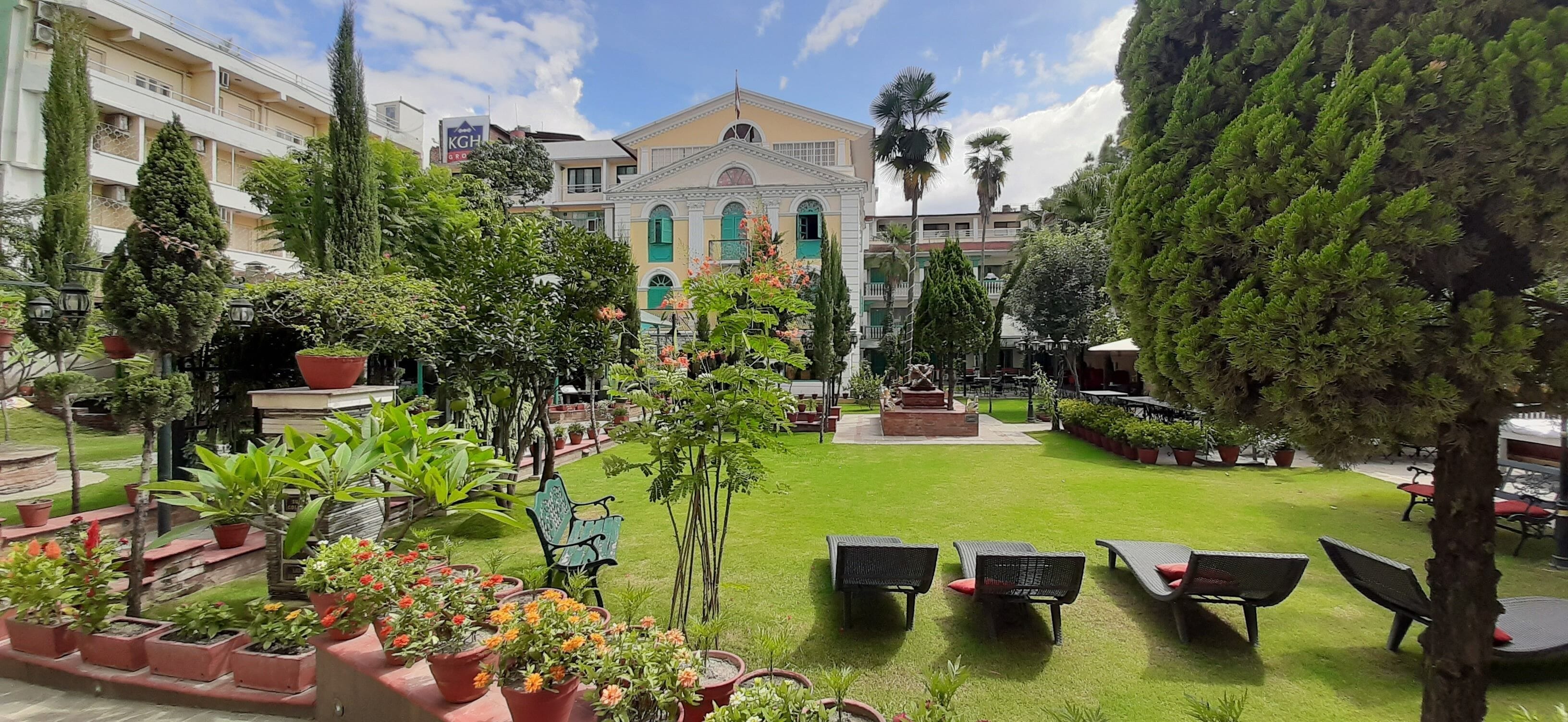 A courtyard with a lawn, potted plants, and outdoor seating.